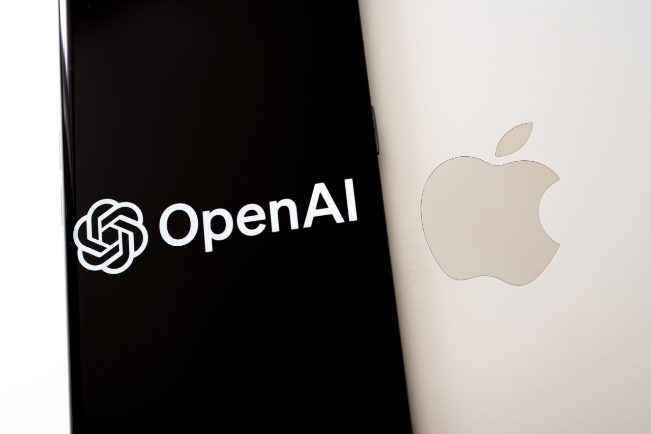 Apple laptop with smartphone on top having OpenAI Logo. Concept for Advanced Technology and AI Leadership.