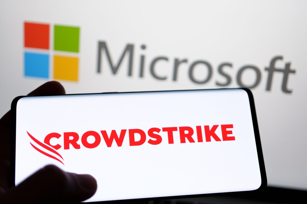 CrowdStrike and Microsoft logo seen on screen of smartphone and laptop. Cybersecurity company behind the global IT outage.