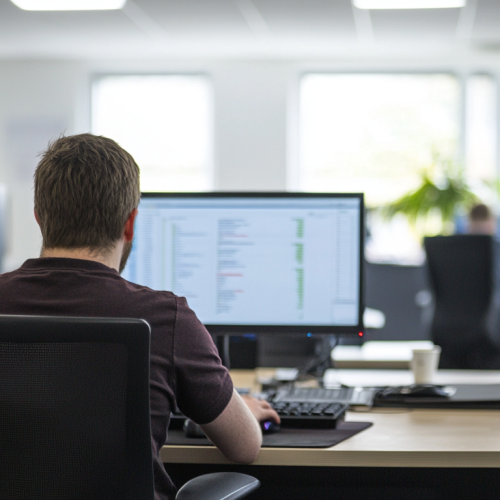 a person sat at a desk in a office for a medium sized IT business in the uk working on a computer